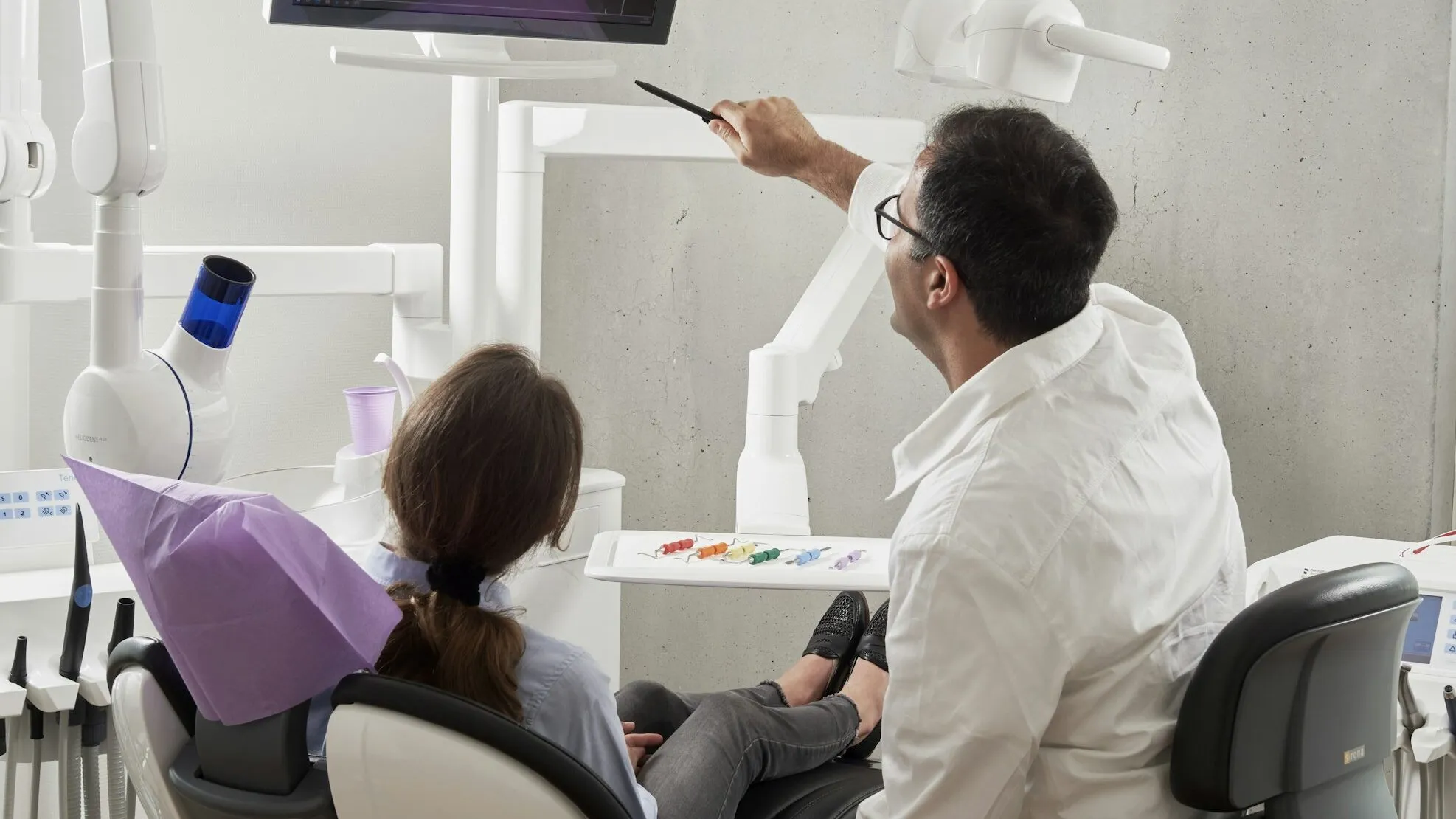 A dentist showing a patient their panoramic dental X-ray on a chairside screen